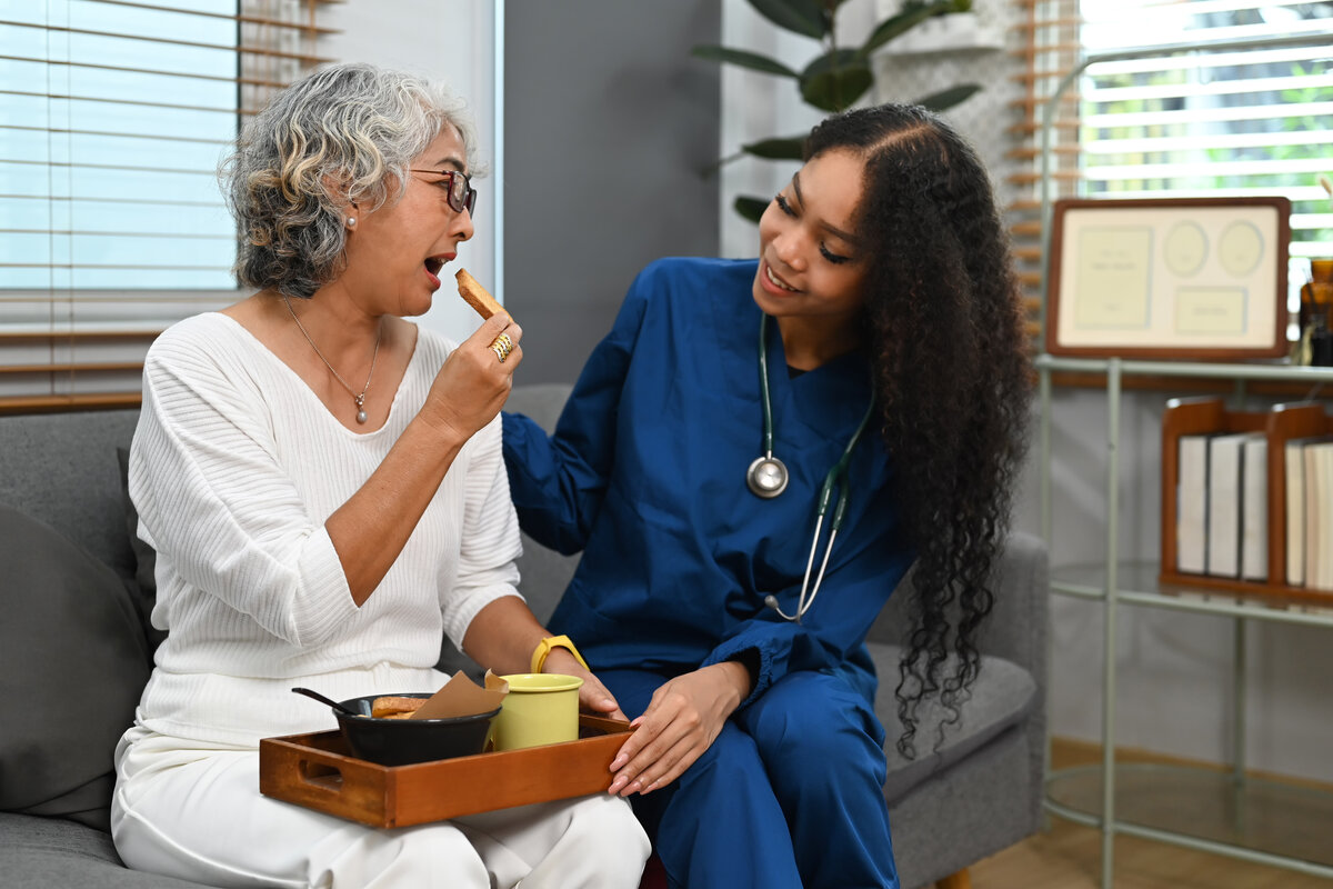 Senior woman enjoying a meal with compassionate caregiver assistance